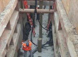 A work crew installing piles to support new sewer and drain pipes